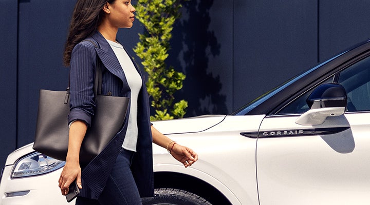 A woman approaches a 2024 Lincoln Corsair® SUV while holding a smartphone. | Koons Lincoln of Bethesda in Silver Spring MD