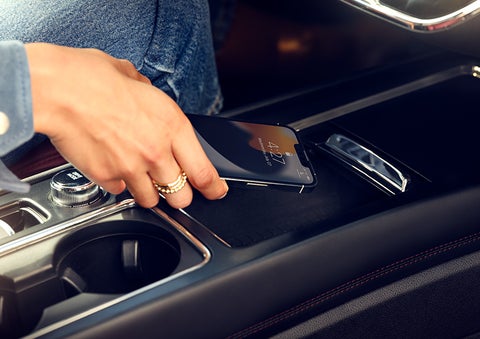 A smartphone is is being placed on the wireless charging pad in the front center console cubby. | Koons Lincoln of Bethesda in Silver Spring MD